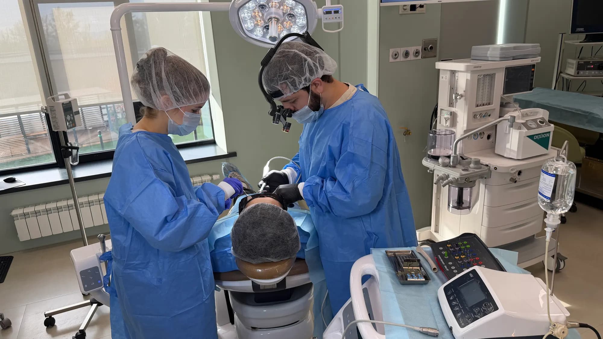 Operating room during a procedure: surgeon, assistant, anesthesia machine and IV line