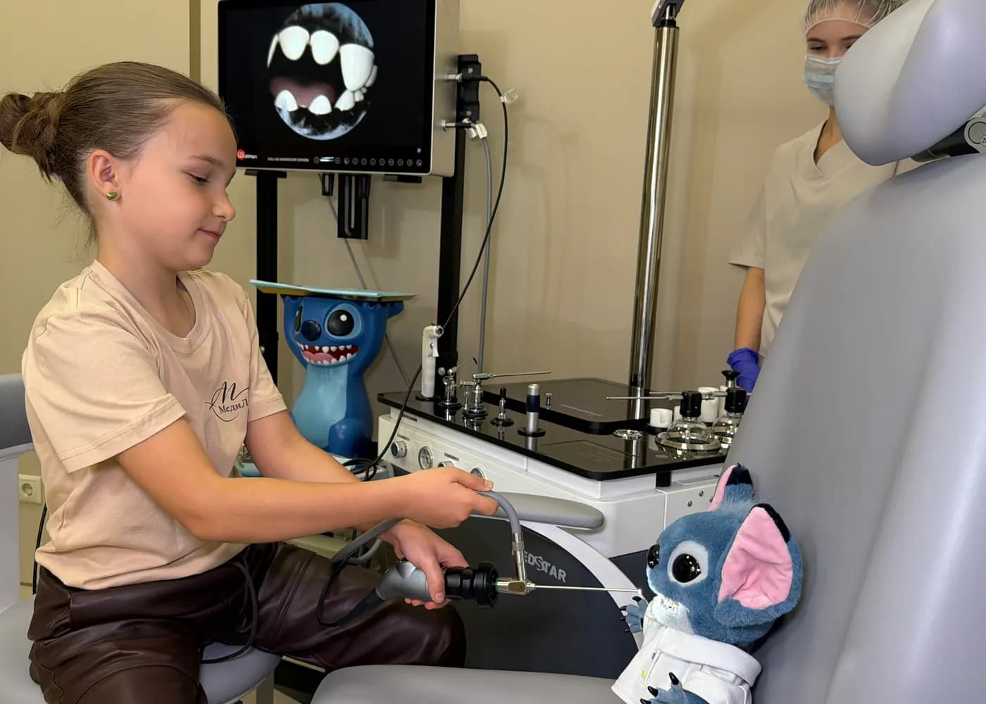 A girl in a dental chair getting to know a dental instrument